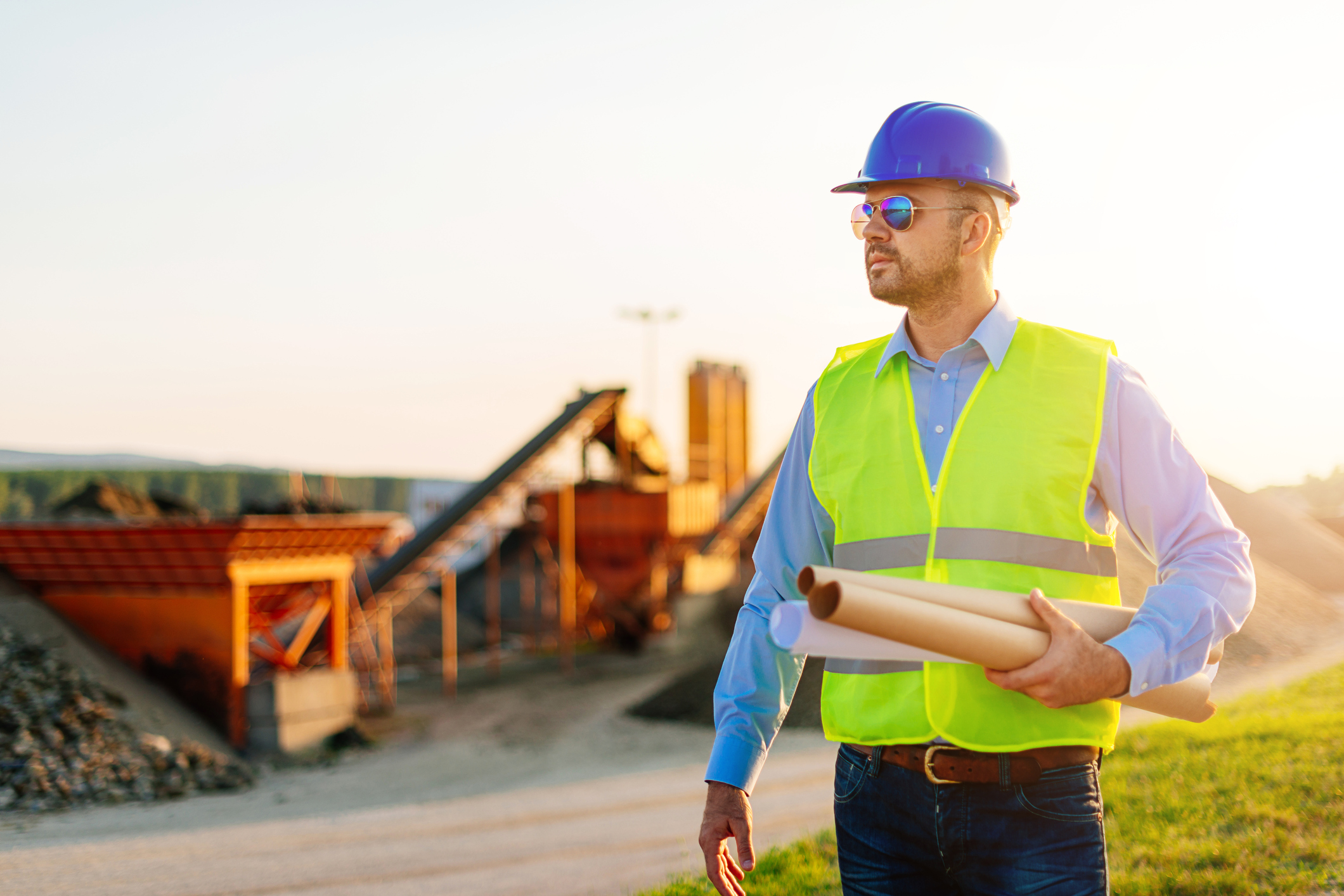 Image of young successful engineer, with blueprints, notepad and digital tablet, observing the project implementation on construction site and in mine. Image taken with Nikon D800 and developed from RAW.